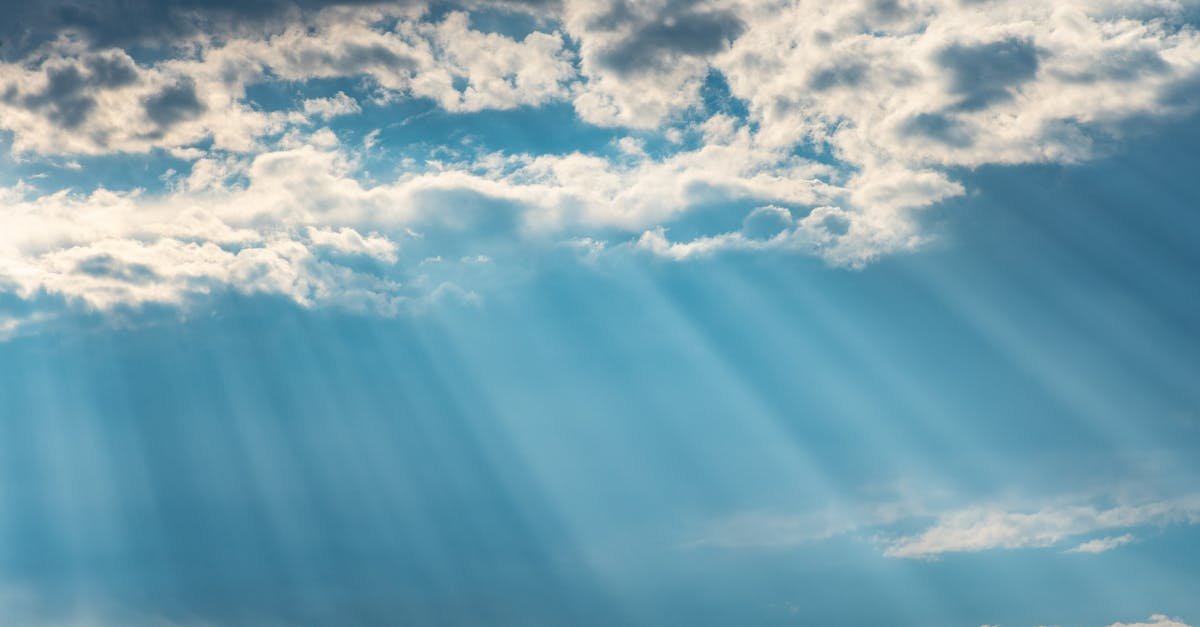 Vibrant sunrays pierce through a cloudy sky, creating a dramatic and dreamy cloudscape.