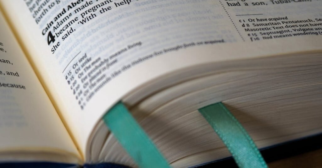 Open Bible showing Genesis, Cain and Abel story, with teal bookmarks.