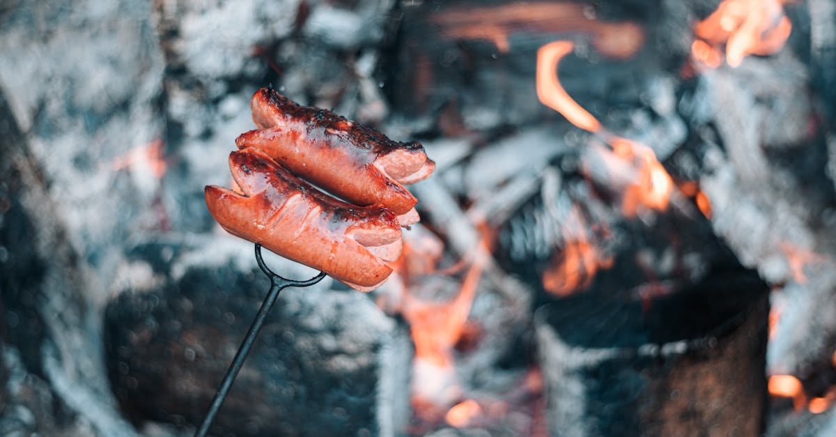 Juicy sausages grilling over open flames on a charcoal barbecue, perfect for outdoor cooking.