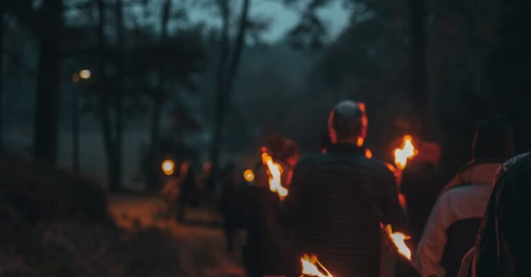 Group walking with torches through a dark forest at night, creating a mystical atmosphere.