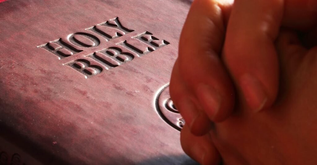 Close-up of hands praying on a Holy Bible, symbolizing faith and spirituality.