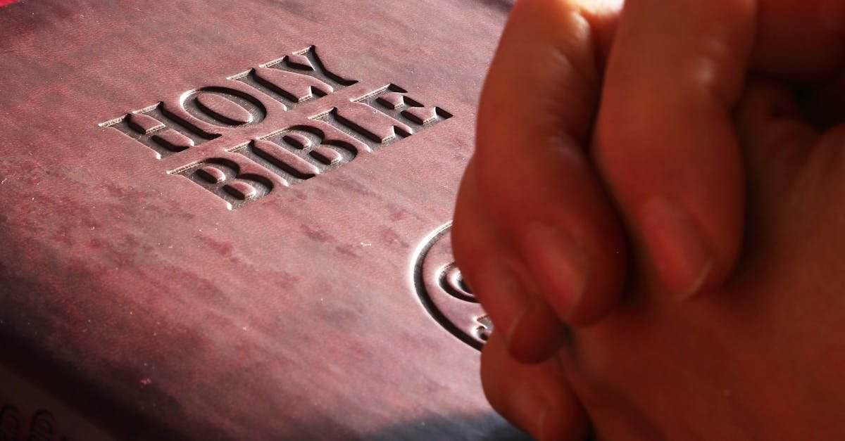 Close-up of hands praying on a Holy Bible, symbolizing faith and spirituality.
