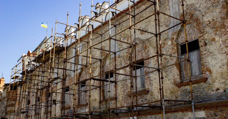 Scaffolding set up on an old brick building under restoration, with a flag above.